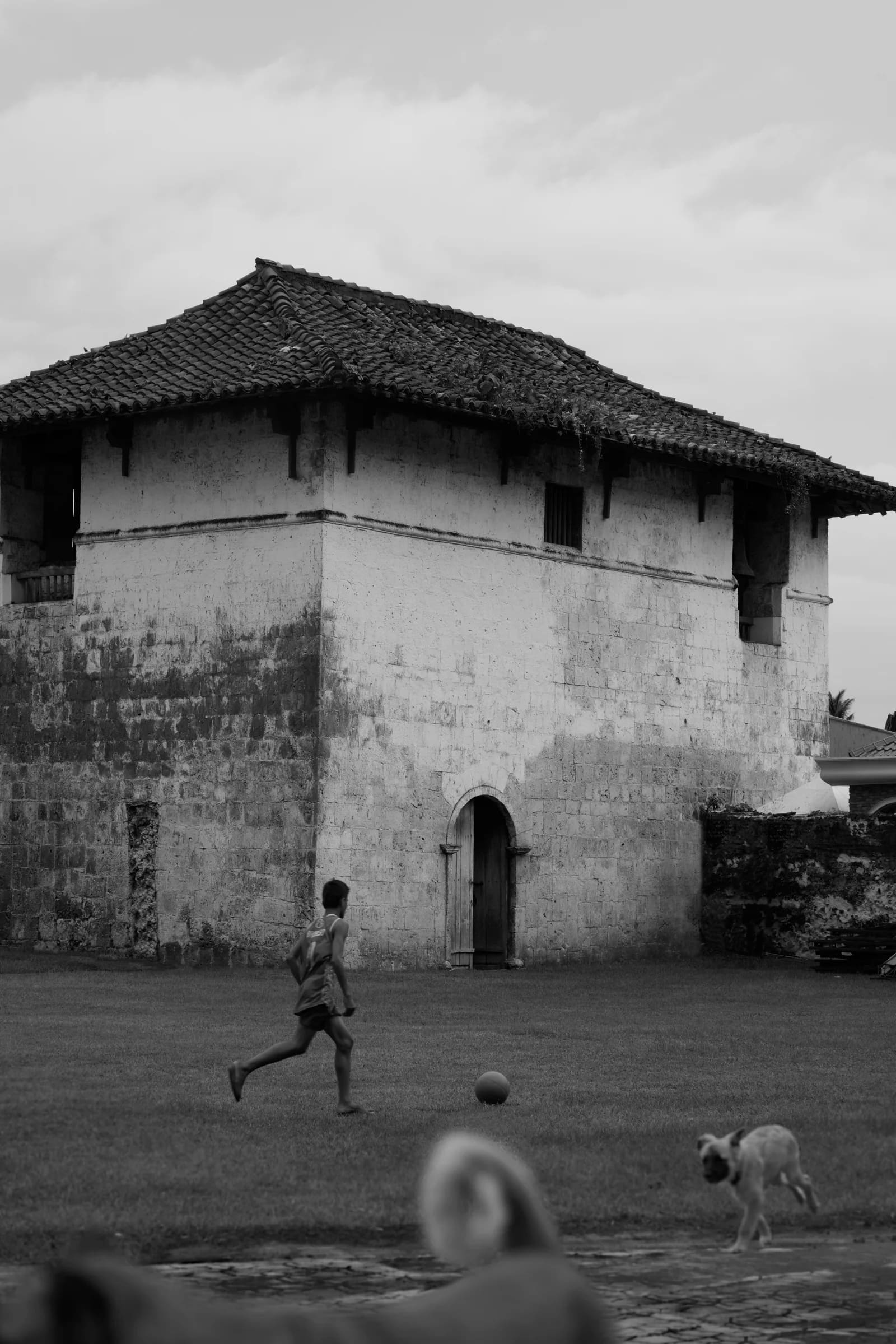 Abhishek Masurkar — street photography, boy playing football by a heritage building